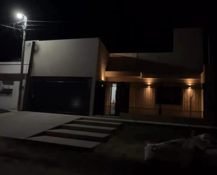 Vivienda terminada de noche, con iluminación cálida en la galería